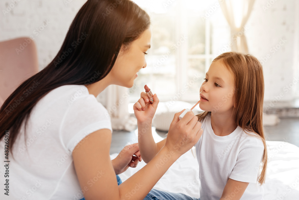 Lovely female and her child organizing home makeup