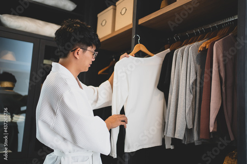 Canvas Print Male asian choosing outfit with closet at home..