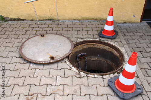 Offener Kanalschacht ist mit Leitkegel abgesichert photo