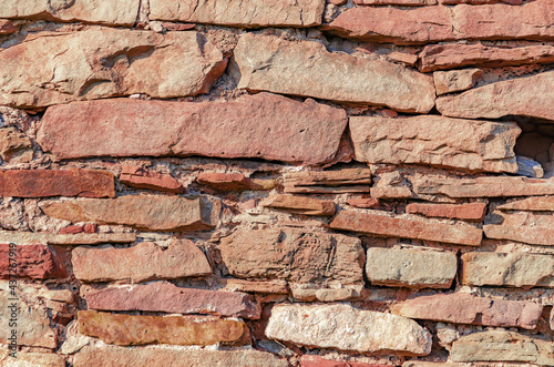 Old vintage stone wall made of untreated red stone