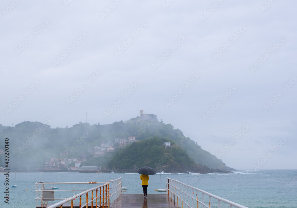 Naklejka premium Woman in the rain on a jetty in the city of Donostia-San Sebastian, Euskadi