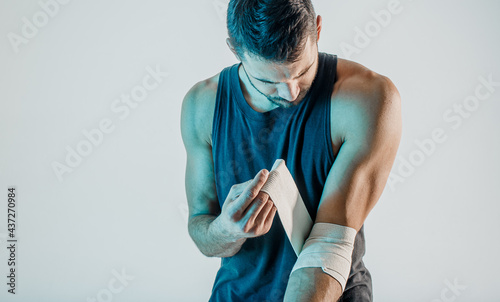 Fotografija Sportsman young wrapping medical bandage on hand