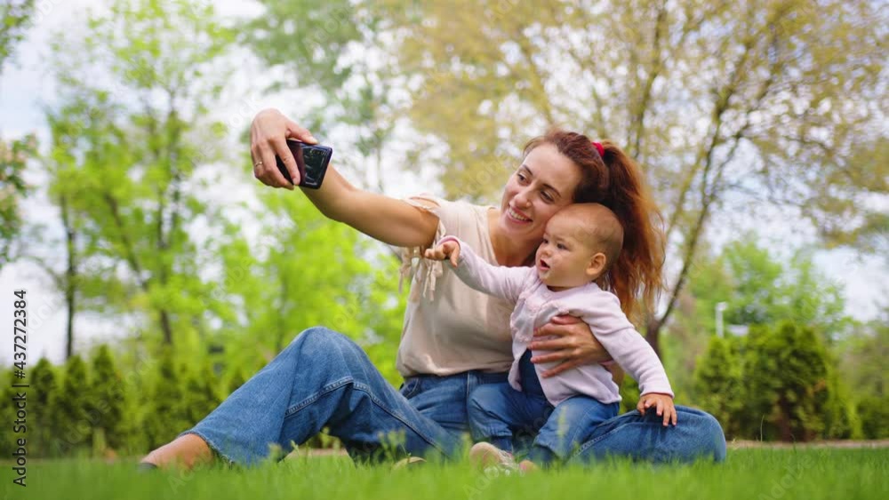 Close up of mother with baby daughter posing for cell phone selfies outdoor. Close up of mother with baby daughter posing for cell phone selfies outdoor.