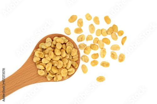 Roasted fava beans for a healthy vegan diet snack food in a wooden spoon and loose on white background. High in protein, vitamins, dietary fibre & nutrients. Flat lay, top view. 
