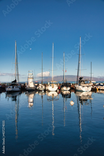 View of the lahaina harbor at dawn with setting moon and lanai in the distance © manuel