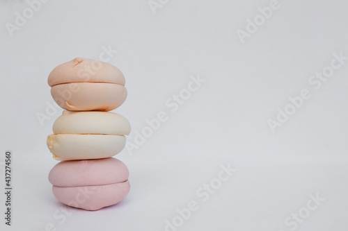 Marshmallow cakes lie in a pyramid on a white background. Colored sweets