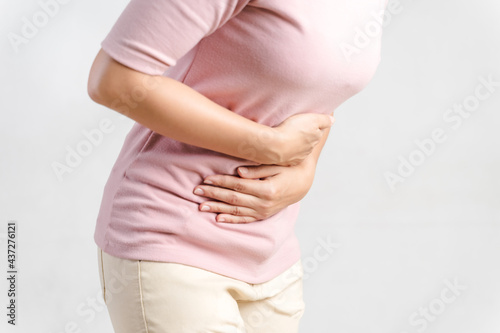 Young woman suffering from strong abdominal pain on white background. Gastritis, Period, menstruation..