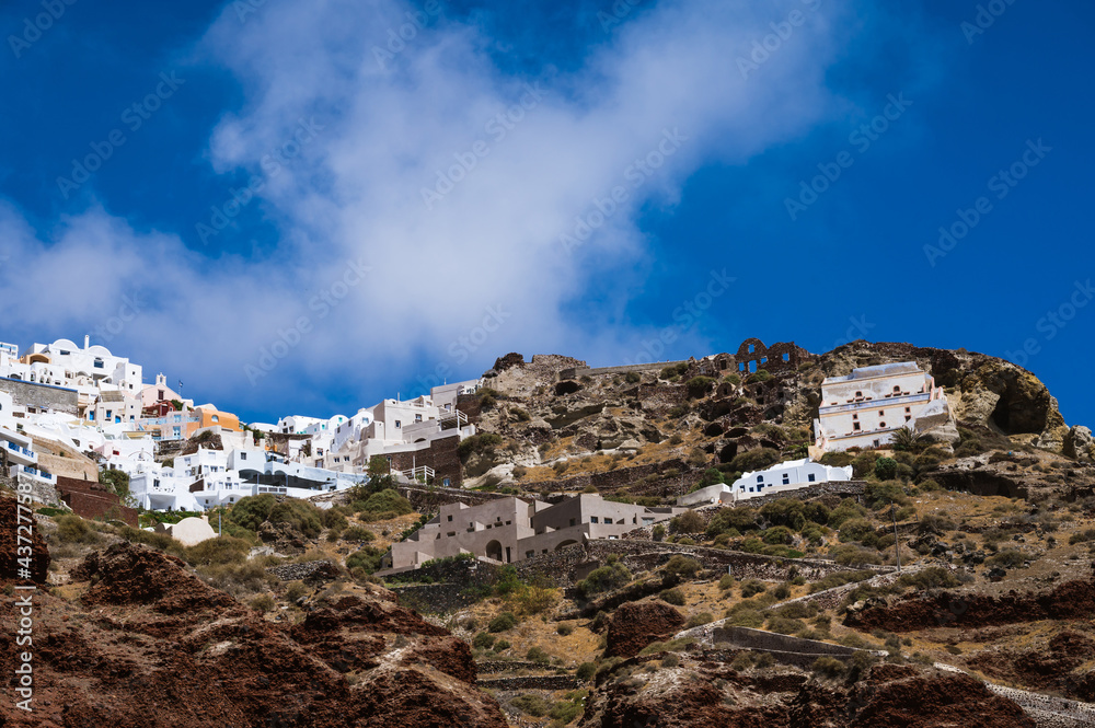 View from sea of Oia up the hill. Santorini, Greece. White city architecture. Luxury tourism. Stairs on the rock.