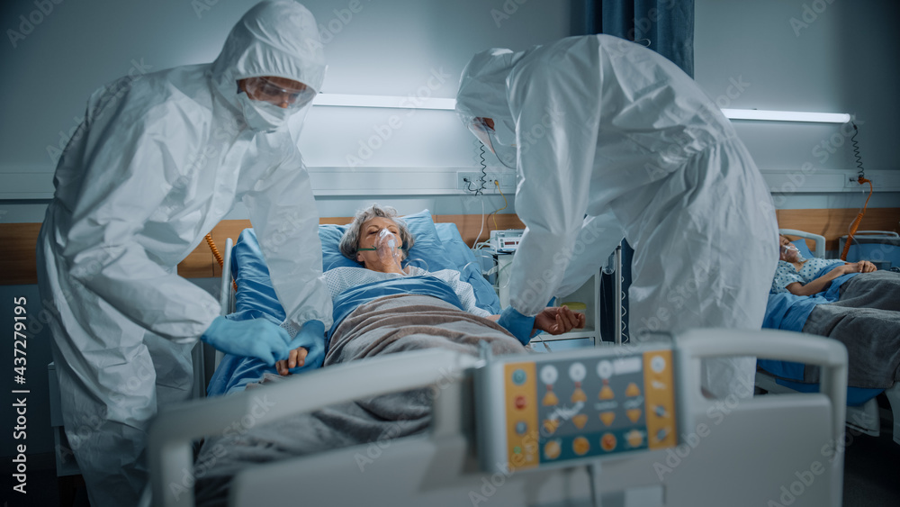 Hospital Coronavirus Emergency Department Ward: Doctors, Paramedics wearing Coveralls, Face Masks Save Life of a Senior Female Patient Lying in Bed with Oxygen Mask, Connect Iv Drip, Heart Rate Sensor Hospital Coronavirus Emergency Department Ward: Doctors, Paramedics wearing Coveralls, Face Masks Save Life of a Senior Female Patient Lying in Bed with Oxygen Mask, Connect Iv Drip, Heart Rate Sensor