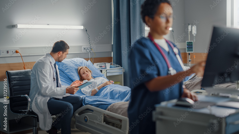 Hospital Ward: Professional Black Female Head Nurse Uses Medical Computer. In the Background Modern Equipment Clinic Doctor Consulting Patient Recovering After Successful Surgery in Bed Hospital Ward: Professional Black Female Head Nurse Uses Medical Computer. In the Background Modern Equipment Clinic Doctor Consulting Patient Recovering After Successful Surgery in Bed