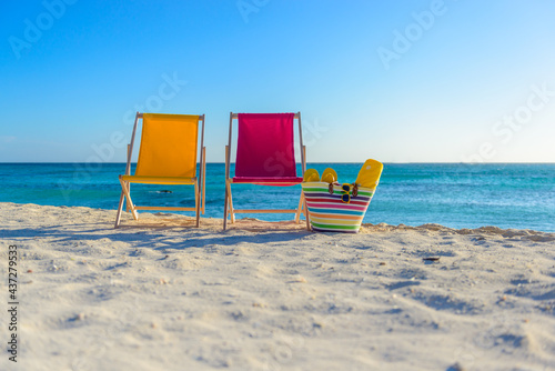 Fototapeta Naklejka Na Ścianę i Meble -  Beach chairs with beach bag on the shoreline at sunset, beautiful beach