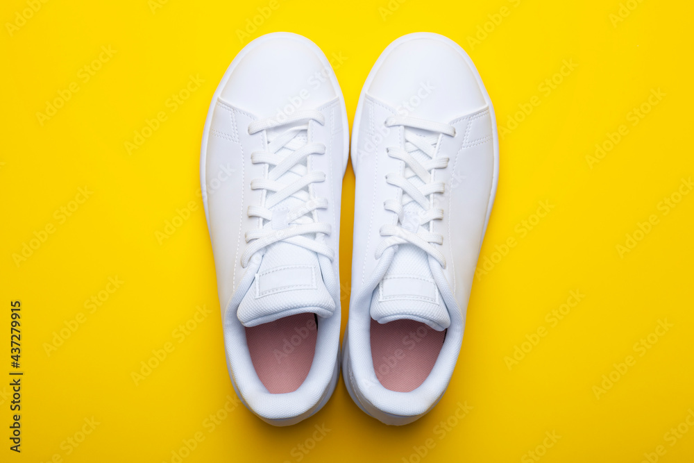 Pair of casual shoes on yellow background. Top view of stylish sneakers on color background Pair of casual shoes on yellow background. Top view of stylish sneakers on color background