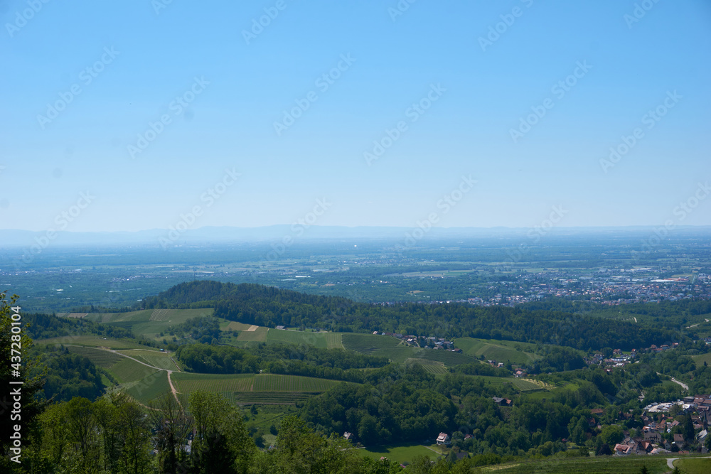 beautiful panorama shot of green meadows, forests, vineyards and blue sky in sasbachwalden 