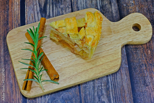 Homemade delicious apple pie slice served on wooden tray.