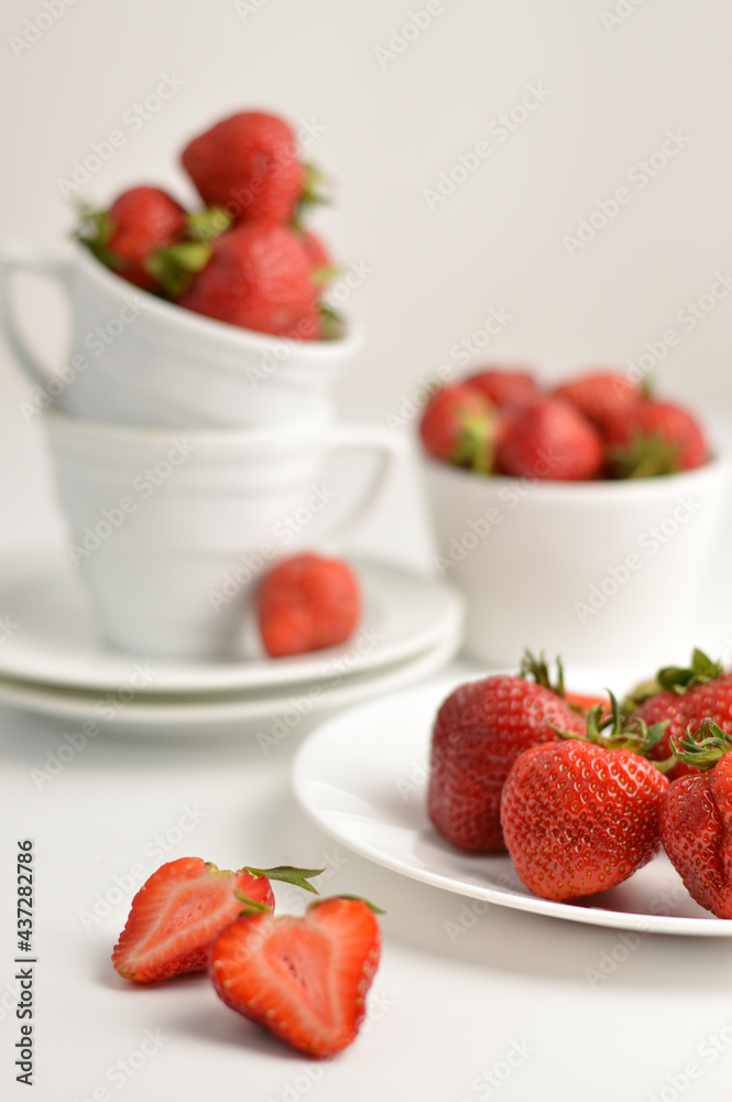 Blurred image of strawberries in a white plate, cup, saucer. Still life with strawberries. Blurred image of strawberries in a white plate, cup, saucer. Still life with strawberries.