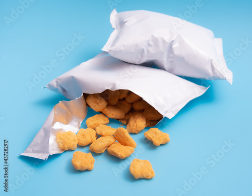 Cuadro en lienzo Corn puff snacks open bag packaging on blue background