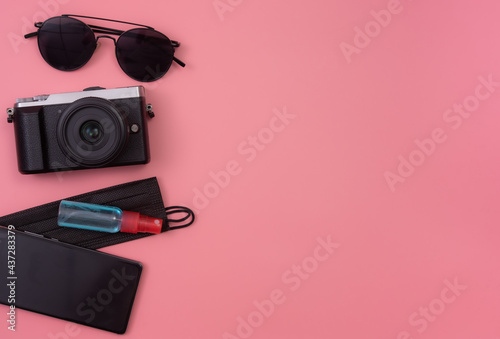 Travel concept:Top view photo of sunglasses compass camera with masks and sanitizer on pink background