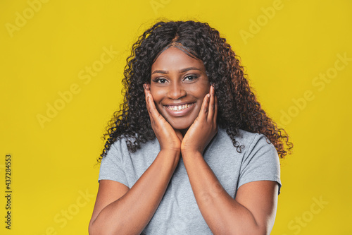 Beautiful african american girl with afro hairstyle smiling with copy space on yellow background