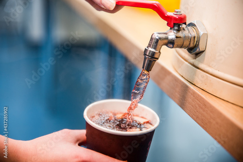 Filling a Christmas cup with red alcoholic Christmas punch. Punch sale at the market, party, Christmas party.