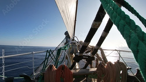 Sunny ocean view from the bow of the sailing ship. Sail, ropes and bell on the deck. photo