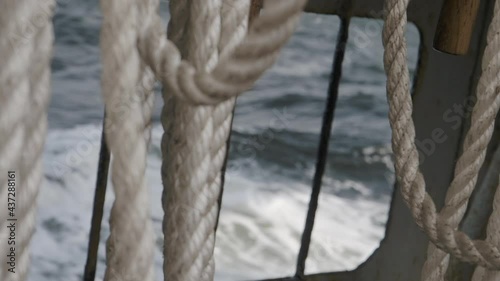 Dirty ropes on the deck of the sail ship. Ocean waves view throught the board.