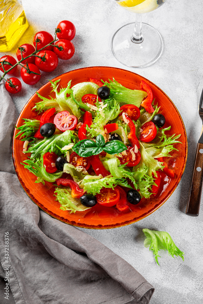 Simple summer salad of lettuce, tomatoes with olives and olive oil on a red plate vertical photo Simple summer salad of lettuce, tomatoes with olives and olive oil on a red plate vertical photo