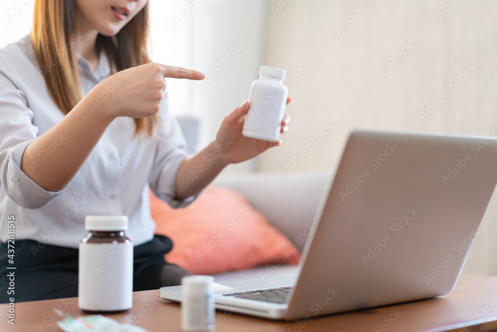 Asian female medical assistant making video call with patients for online support, Woman explaining medicine bottles working from home while coronavirus pandemic Asian female medical assistant making video call with patients for online support, Woman explaining medicine bottles working from home while coronavirus pandemic