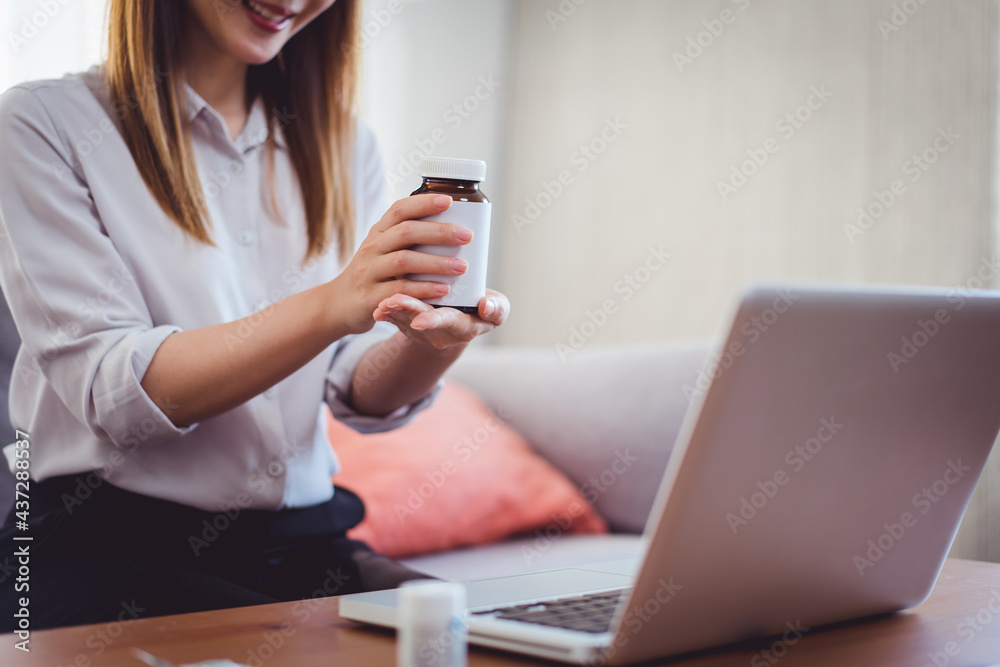 Asian female medical assistant making video call with patients for online support, Woman explaining medicine bottles working from home while coronavirus pandemic Asian female medical assistant making video call with patients for online support, Woman explaining medicine bottles working from home while coronavirus pandemic