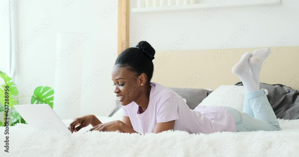 Thoughtful woman typing on laptop in bed at home Thoughtful woman typing on laptop in bed at home