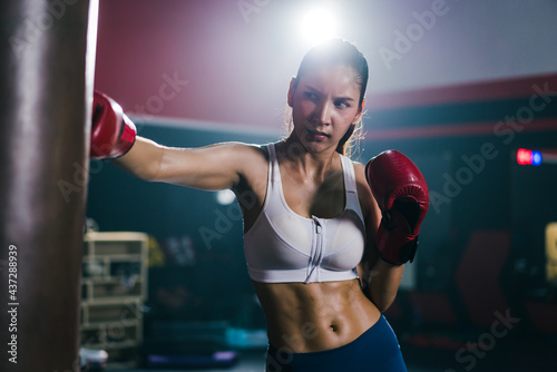 Young Asian is punching a sandbag training boxing or Muay Thai in the gym. Concept of Boxer and fitness © structuresxx