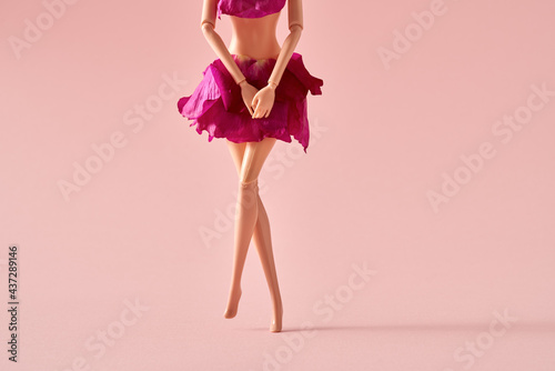 Plastic woman figure dressed in rose petals crossing legs as if wanting to pee or having menstrual pain