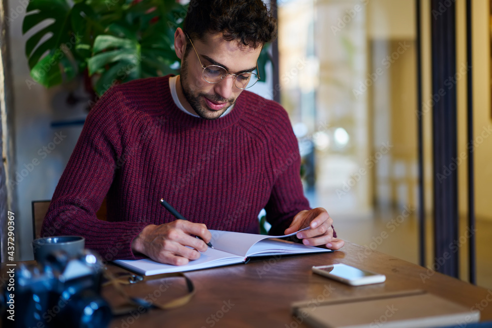 Focused man writing in notebook sitting at desk Focused man writing in notebook sitting at desk