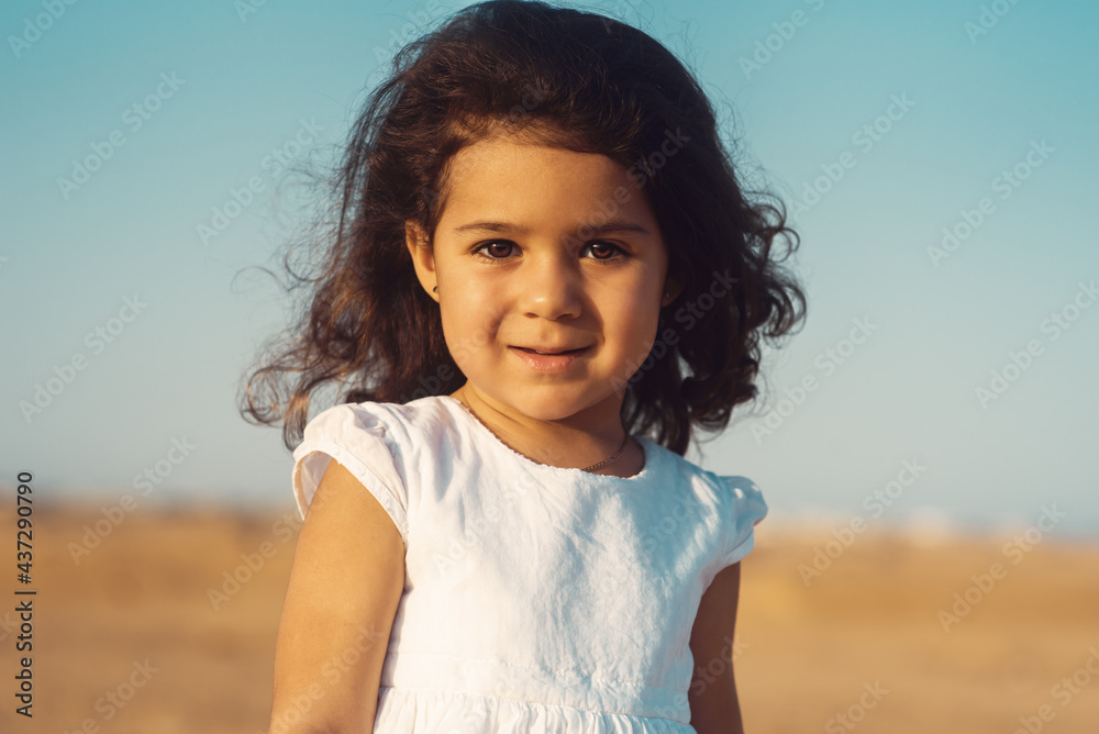 A portrait of a Muslim little girl in the desert. A girl of oriental appearance at sunset. Face of a beautiful Egyptian girl A portrait of a Muslim little girl in the desert. A girl of oriental appearance at sunset. Face of a beautiful Egyptian girl