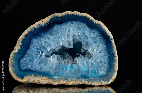 Cross section of natural stone. Quartz geode with transparent crystals on a black mirror background..