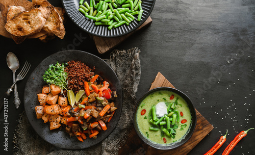 Buddha bowl salad with salmon, red quinoa, baked vegetables, micro greens, peas cream soup with green beans in bowl on dark wooden background. Healthy vegan food, clean eating, dieting, top view