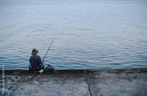 a man on the seashore is fishing. fisherman resting on the river at dawn