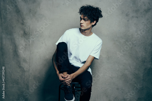 man with curly hair sitting on a chair fashion studio