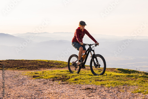 Woman riding mountain bike into the sunset. Beautiful golden summer light. © 24K-Production
