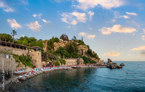 Fototapeta Naklejka Na Ścianę i Meble -  Mermerli Beach view from hill in Antalya City. Coast stone embankment with tall cliff and Mermerli Beach in Kaleici district, Antalya, Turkey