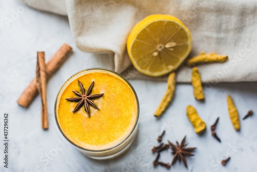 Healthy Ayurvedic drink with golden almond milk or turmeric latte with turmeric powder on a light background close-up. Trendy asian natural detox drink with spices for vegans