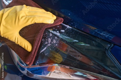 A man cleaning the car with a microfiber cloth and a spray bottle. Concept of car detail (or dump). Selective focus.