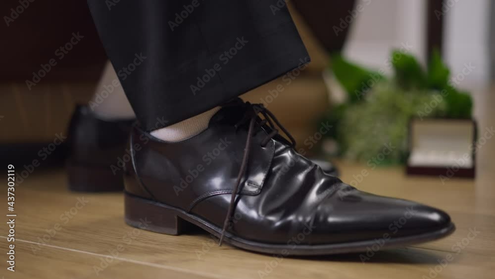 Side view close-up male foot in leather luxurious black shoe stomping. Unrecognizable nervous man in formal elegant footwear waiting indoors. Lifestyle and elegance concept Side view close-up male foot in leather luxurious black shoe stomping. Unrecognizable nervous man in formal elegant footwear waiting indoors. Lifestyle and elegance concept