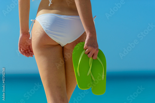 Woman with bikini and flip flops on the beach In Aruba © TRAVEL EASY