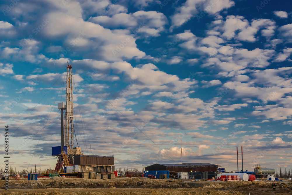 A site in the northern tundra at an oil and gas field. Drilling rig for drilling wells. Infrastructure and drilling equipment for drilling operations. Beautiful expressive sky