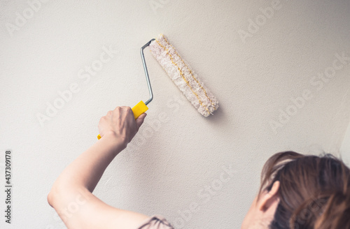 woman use the white textured paint to wall photo
