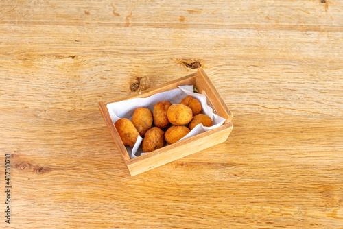 Spanish tapa of Iberian ham croquettes in wooden container and on wooden table