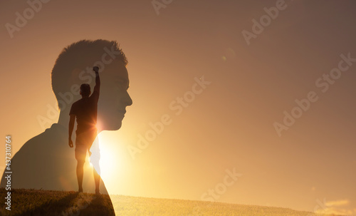 Silhouette of strong young man feeling determined, empowered and motivated putting fist up to the sky. People power and inner strength concept.  photo