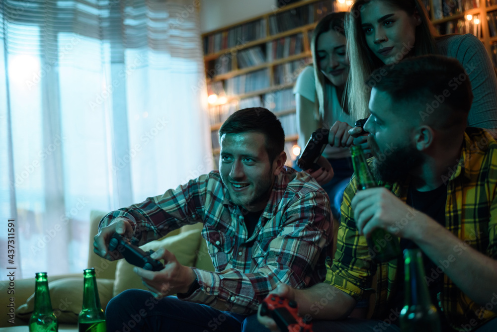 A group of friends playing video games while relaxing at home A group of friends playing video games while relaxing at home