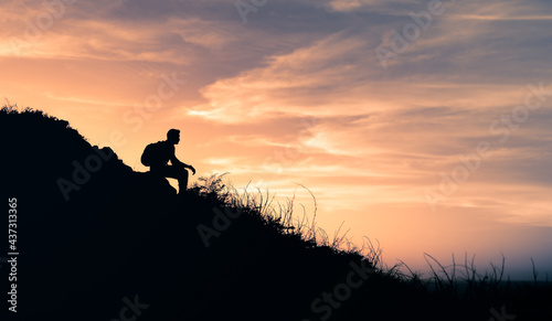 Silhouette of a person sitting on a mountain edge looking at the view. 