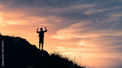 Male hiker celebrating on top of mountain. Victory, strength and adventure concept. 